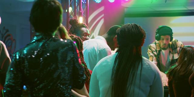 DJ masasının önündeki pistte dans eden bir grup, arkadan